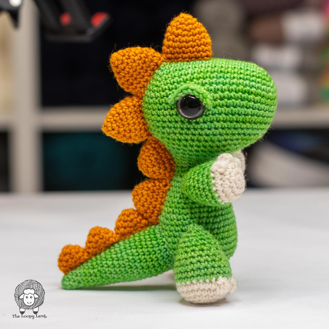 green, orange, and white crocheted amigurumi dinosaur