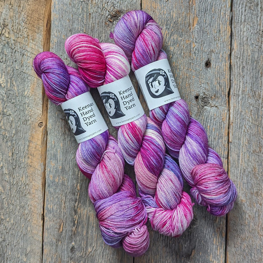 Multicolored sock yarn with pink, magenta, periwinkle, and violet on a wooden background